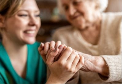 Zorgverlener houdt de hand vast van een oudere vrouw