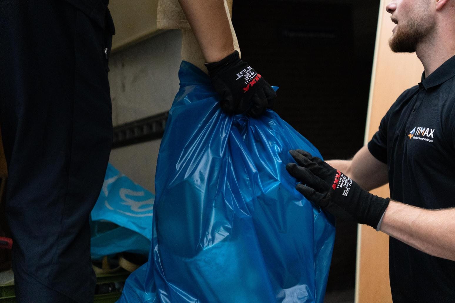 Timax ontruimingen 18 Medewerker van Timax draagt een zak met inboedel tijdens een ontruiming